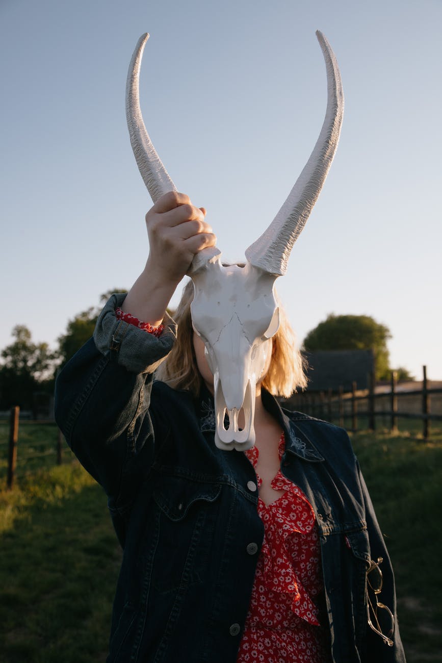 faceless woman with bull skull in countryside